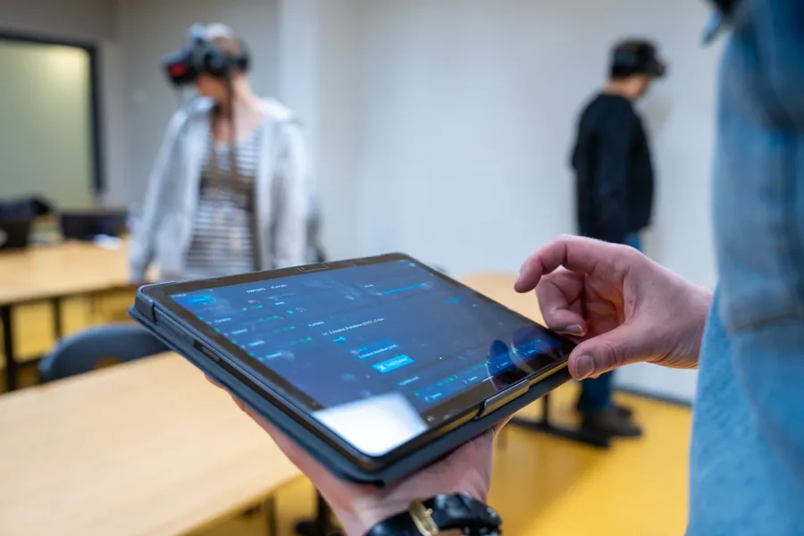 A tablet controlling a VR session while two students wear headsets in a classroom