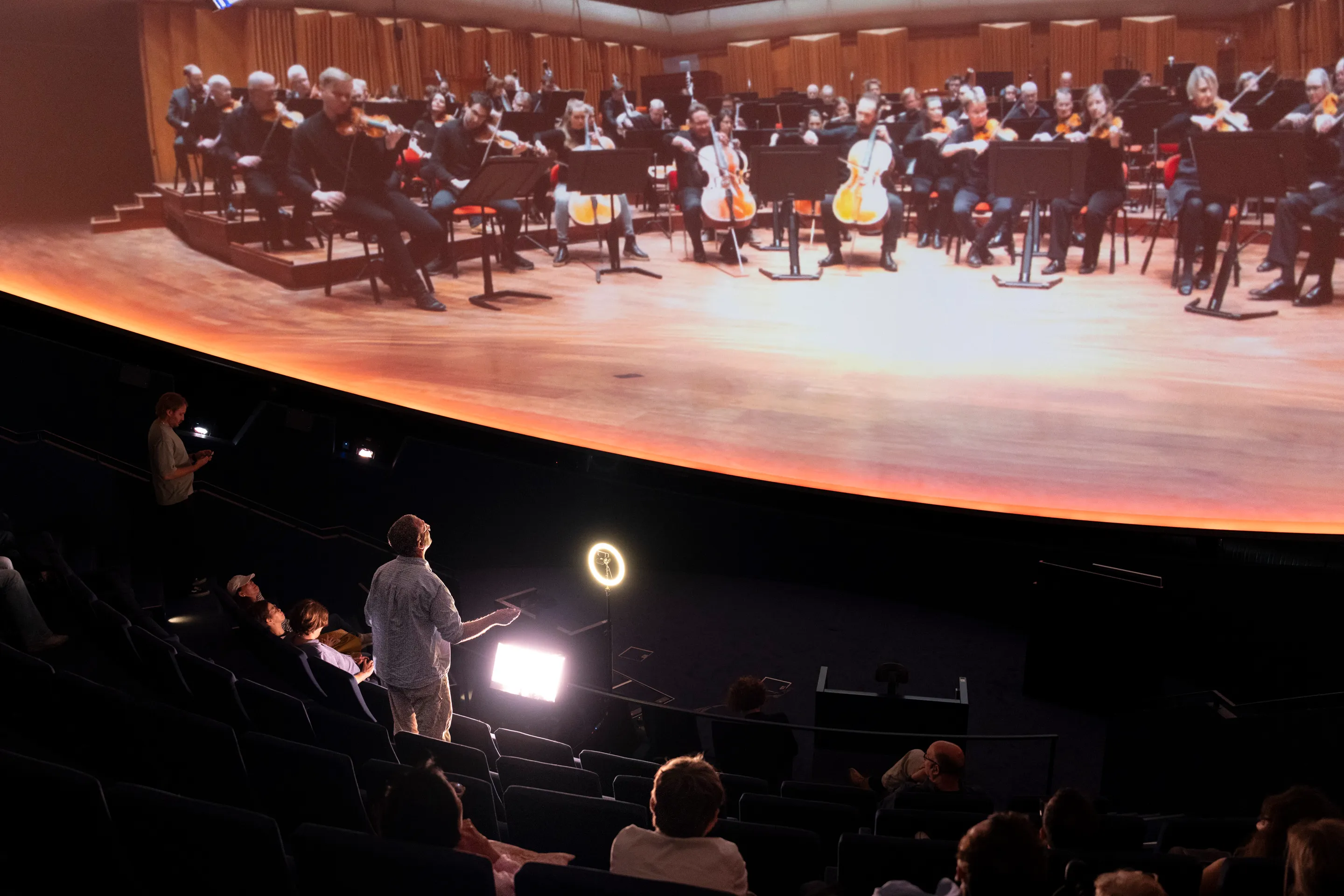 A visitor conducting the Swedish Radio Symphony Orchestra projected across the fulldome
