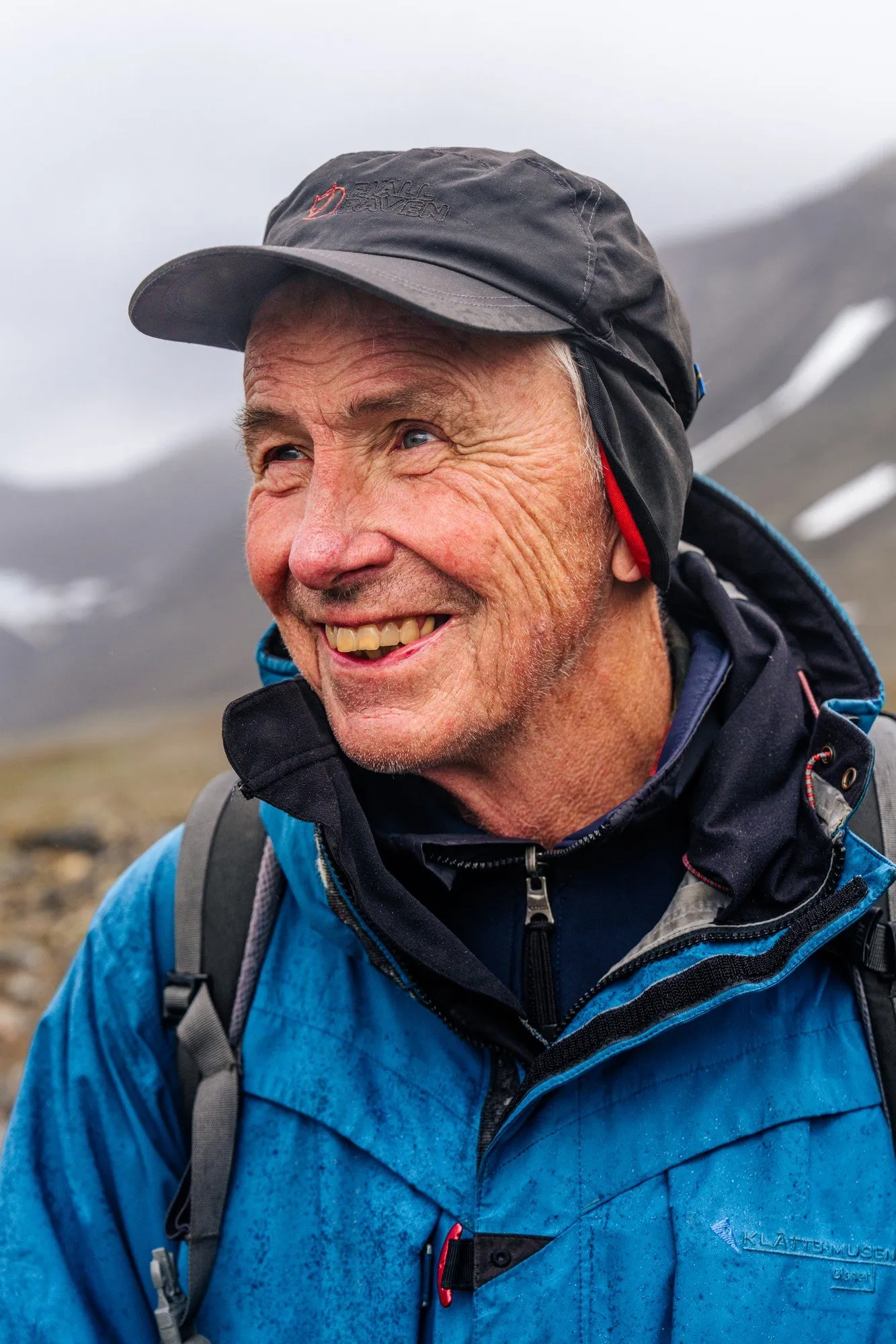 Glaciologist Per Holmlund smiling in the Tarfala valley, snow-streaked mountains behind him
