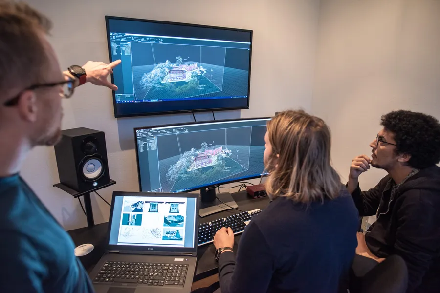 Three participants working through a 3D scan on two screens during a workshop